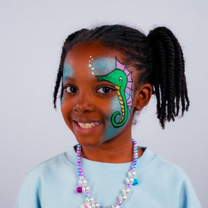 Final step, Using black paint to outline the seahorse, adding an eye, decorating the other side with thin swirls, highlighting the seahorse with white paint, and adding air bubbles to complete the Seahorse face paint.