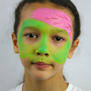 Step two, adding green paint to middle of face and pink on side of forehead.